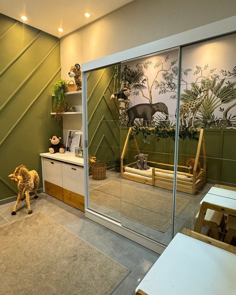 Quarto infantil em temática safari. À esquerda uma parede verde com textura. Em primeiro plano um guarda-roupa com espelhos em frente a uma parede branca.